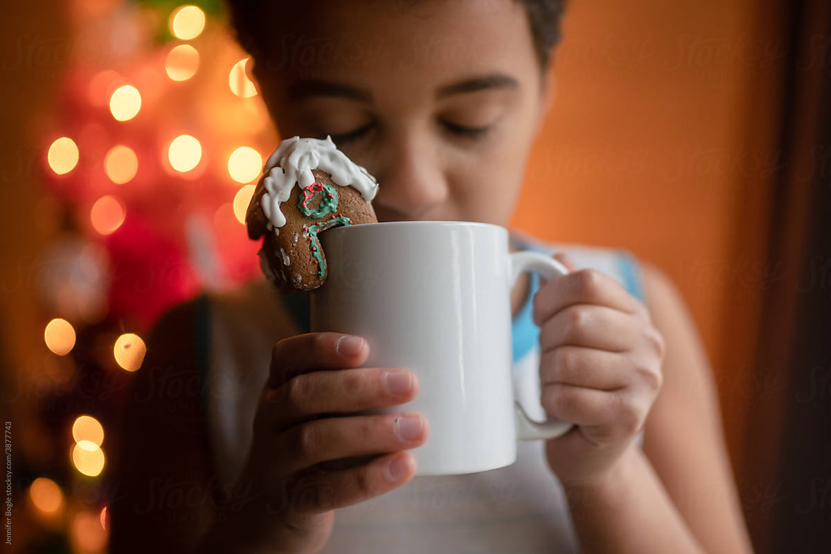 child drinks from mug with mini gingerbread house