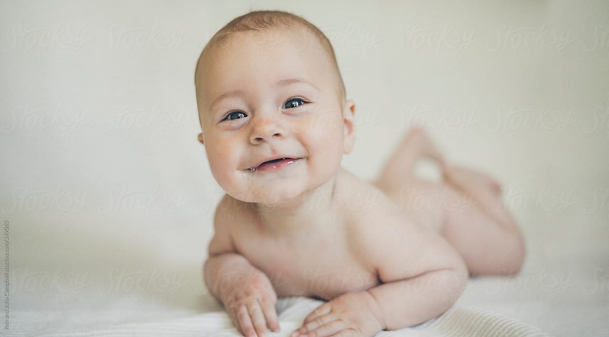 Cute, happy baby boy on tummy - solid background