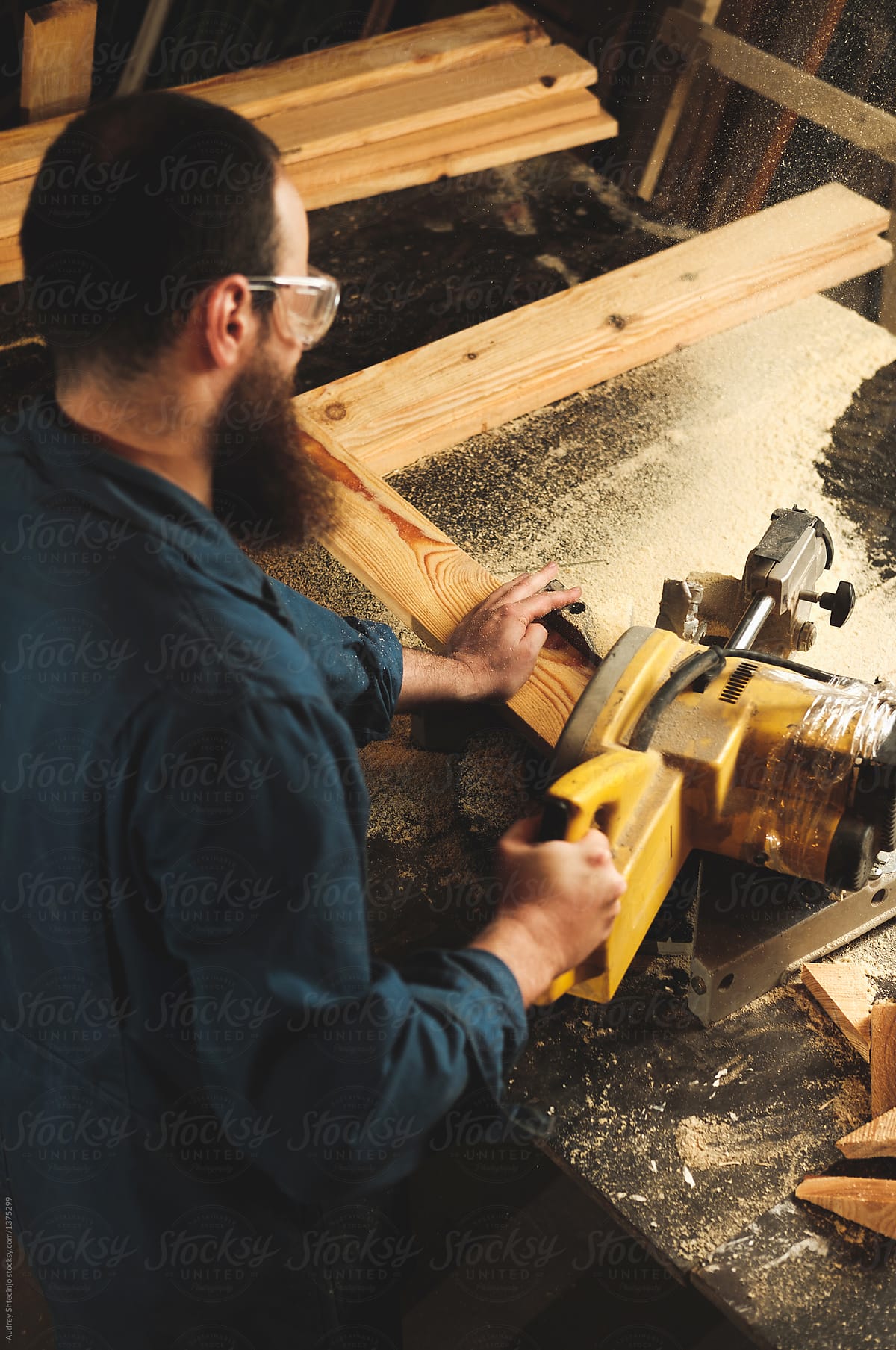 Carpenters working in workshop/sawmil with wood on circular saw.