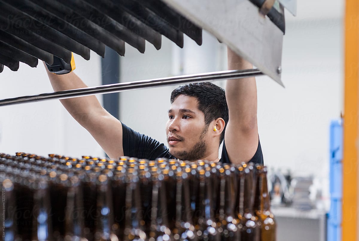 Industrial worker loading bottles in assembly line