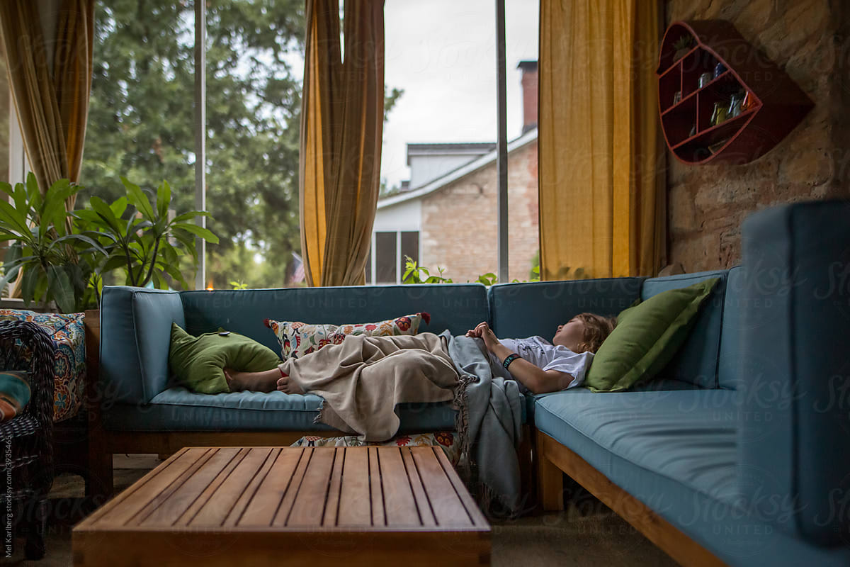 Young boy lying on couch on screened in porch