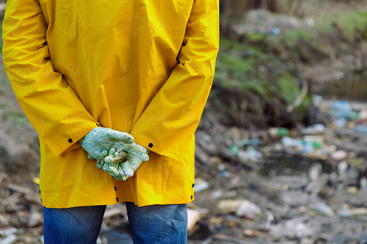 Person folding hands behind back and looking at plastic pollution