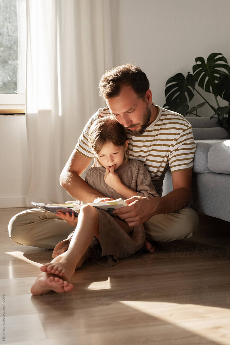 Dad helping kid to read book
