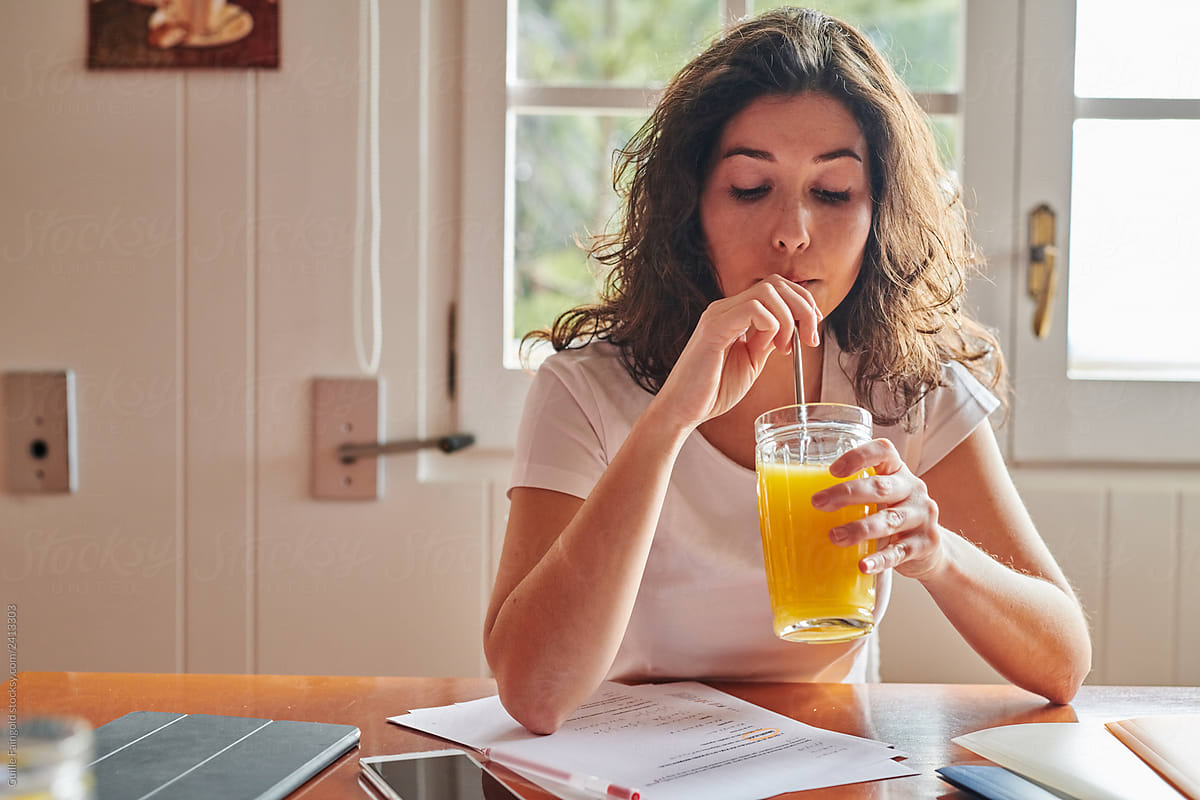 Relaxed female student with orange juice at home