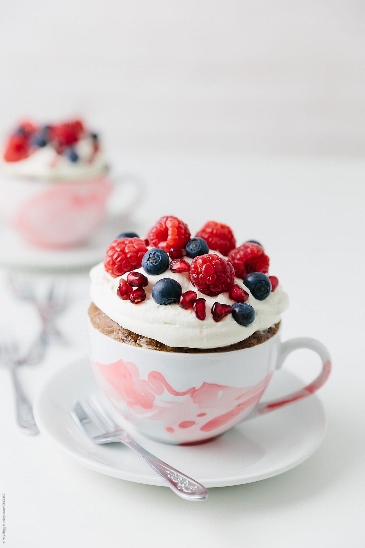 Mug cake microwave dessert with cream and berries on top