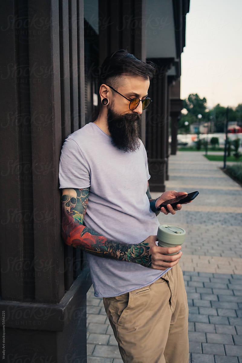 Man in sunglasses drinking coffee and using smartphone