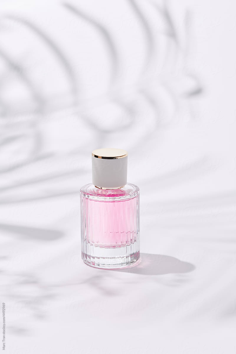 Bottle of essence perfume on white background with sunlight
