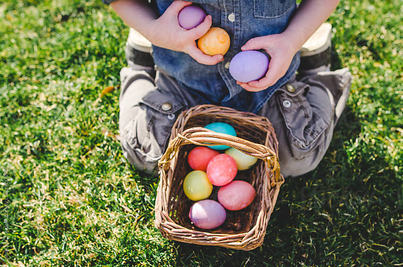 Child kneeling in grass with Easter eggs