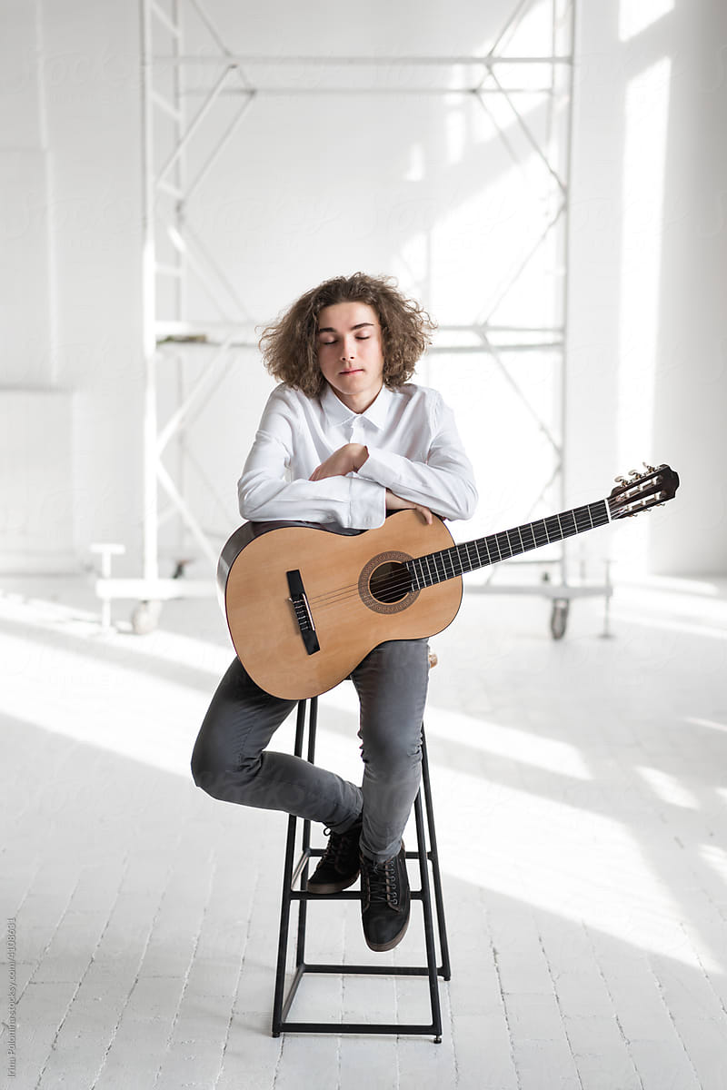 Portrait of a young boy with a guitar in white studio