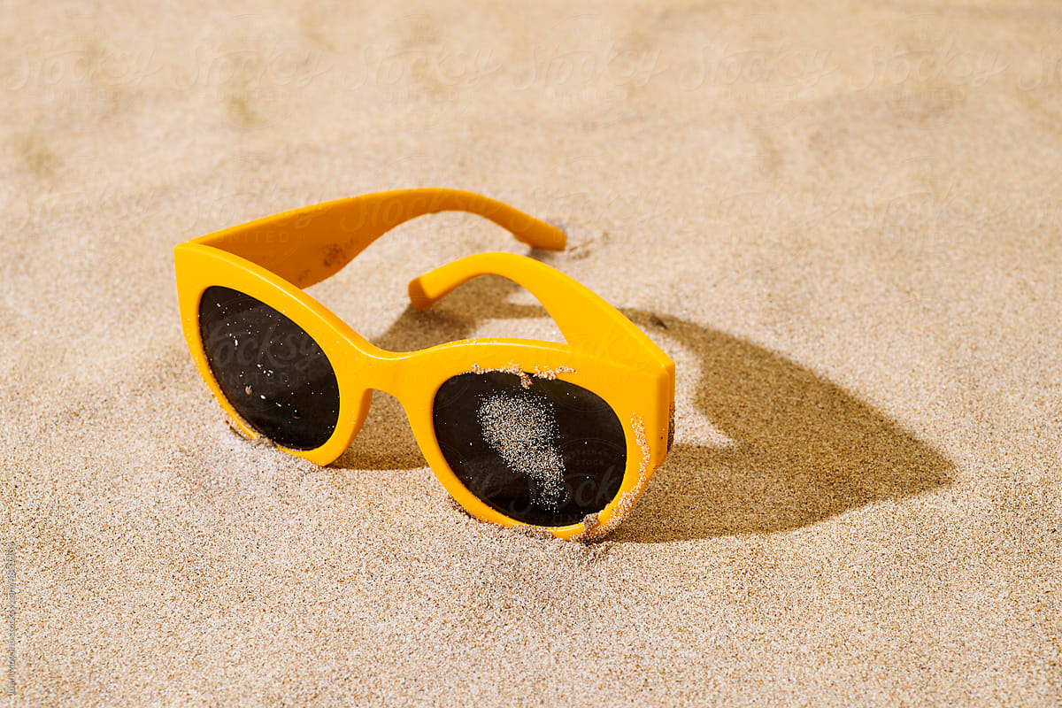 yellow sunglasses on the sand of a beach