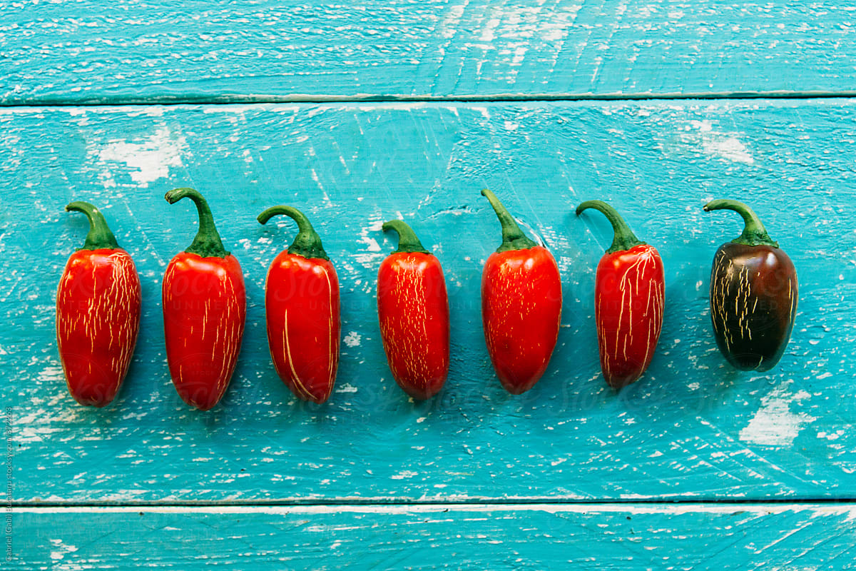 Group Of Five In-line Red Jalapeno Peppers And One Green by Stocksy  Contributor Gabi Bucataru - Stocksy