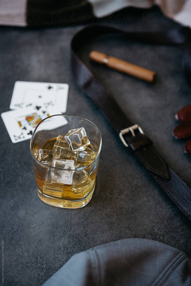 Glass of whisky near playing cards and a cigar