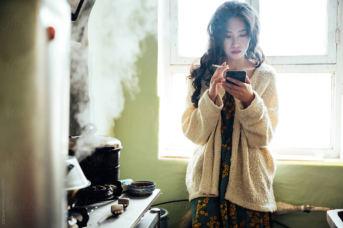 Young woman smoking in the kitchen