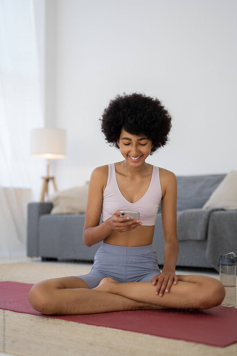Woman Uses the Phone While Relaxing After Doing Yoga