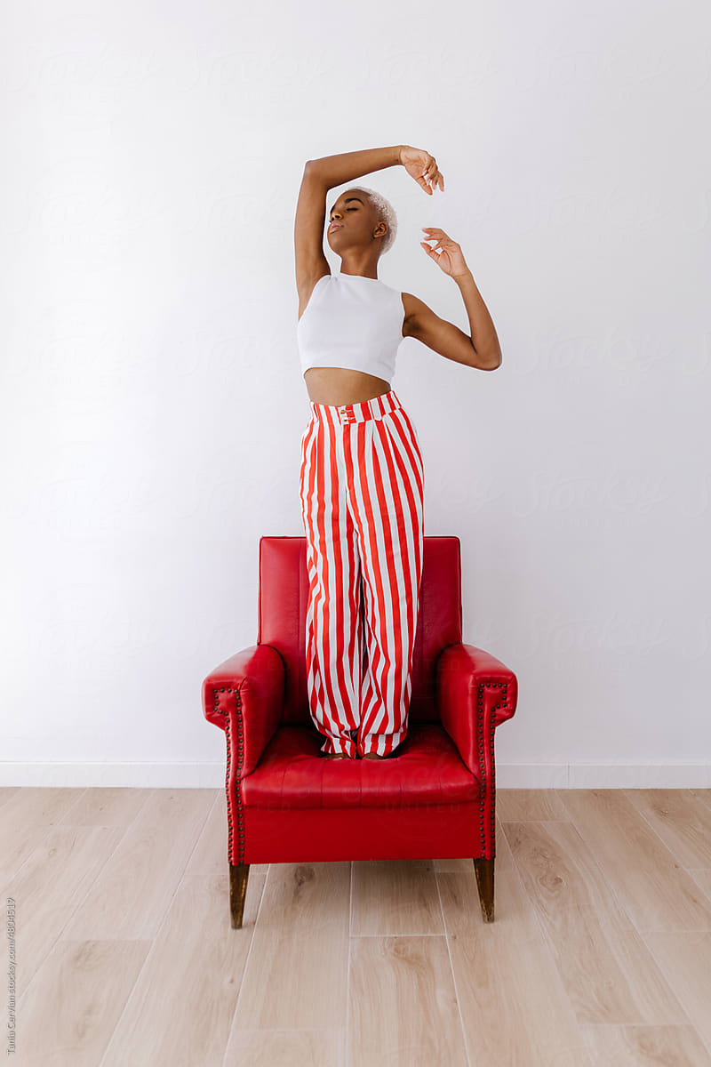 Graceful African American woman standing on armchair