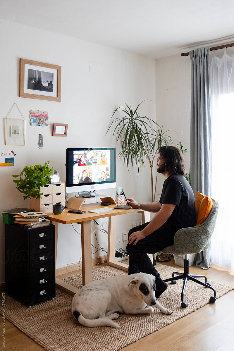 Young designer in video call in home office with dog
