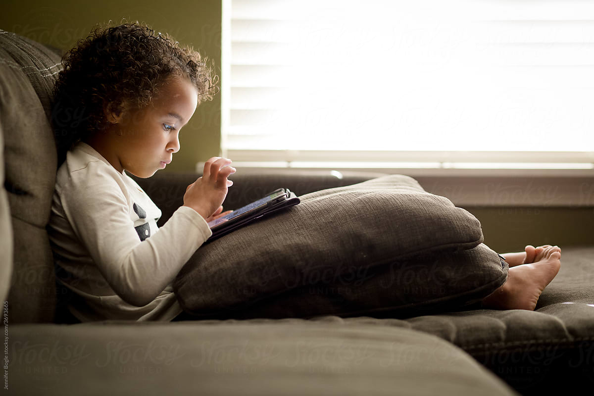 Preschooler focused on tablet on couch