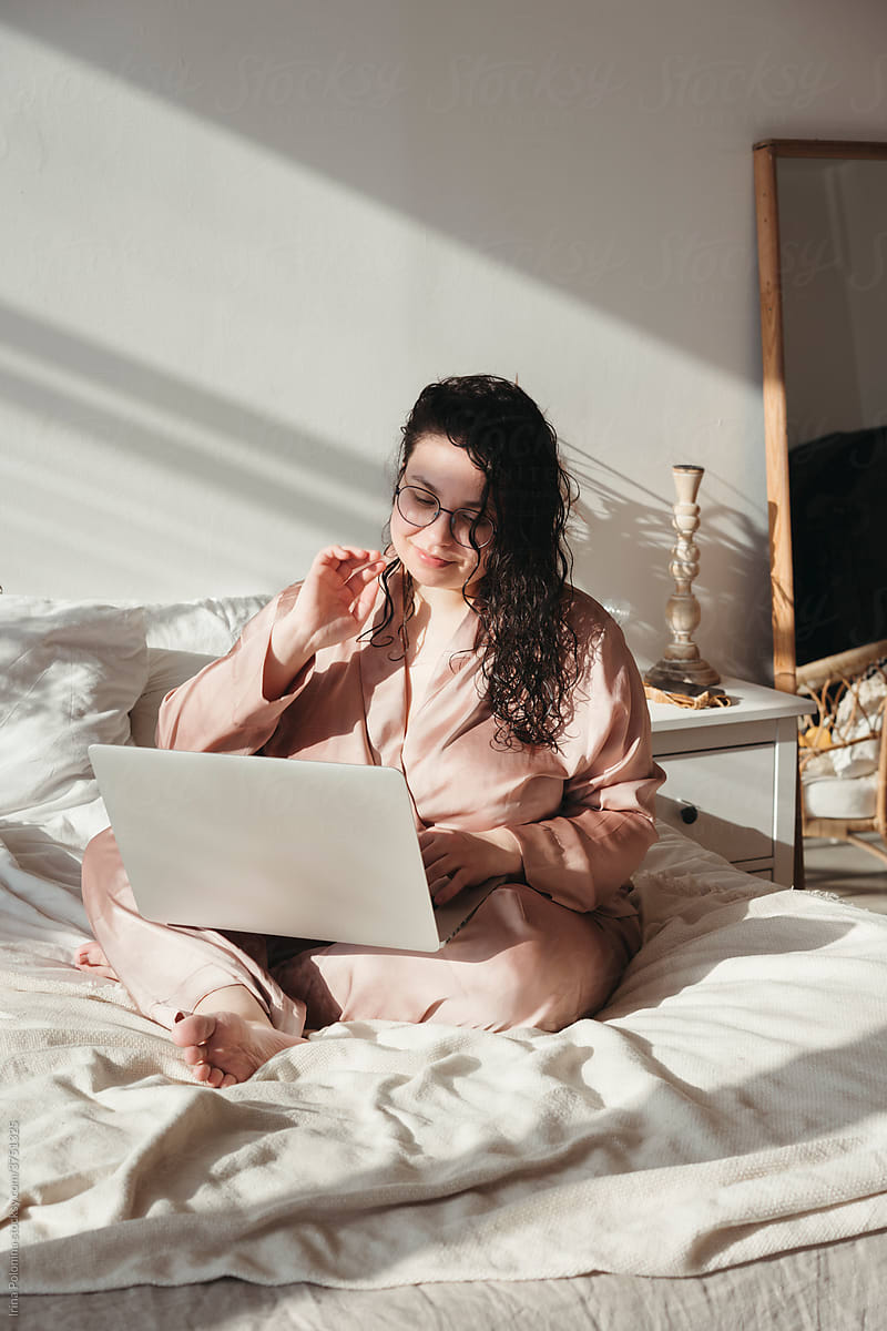 Curvy content woman uses laptop at home.