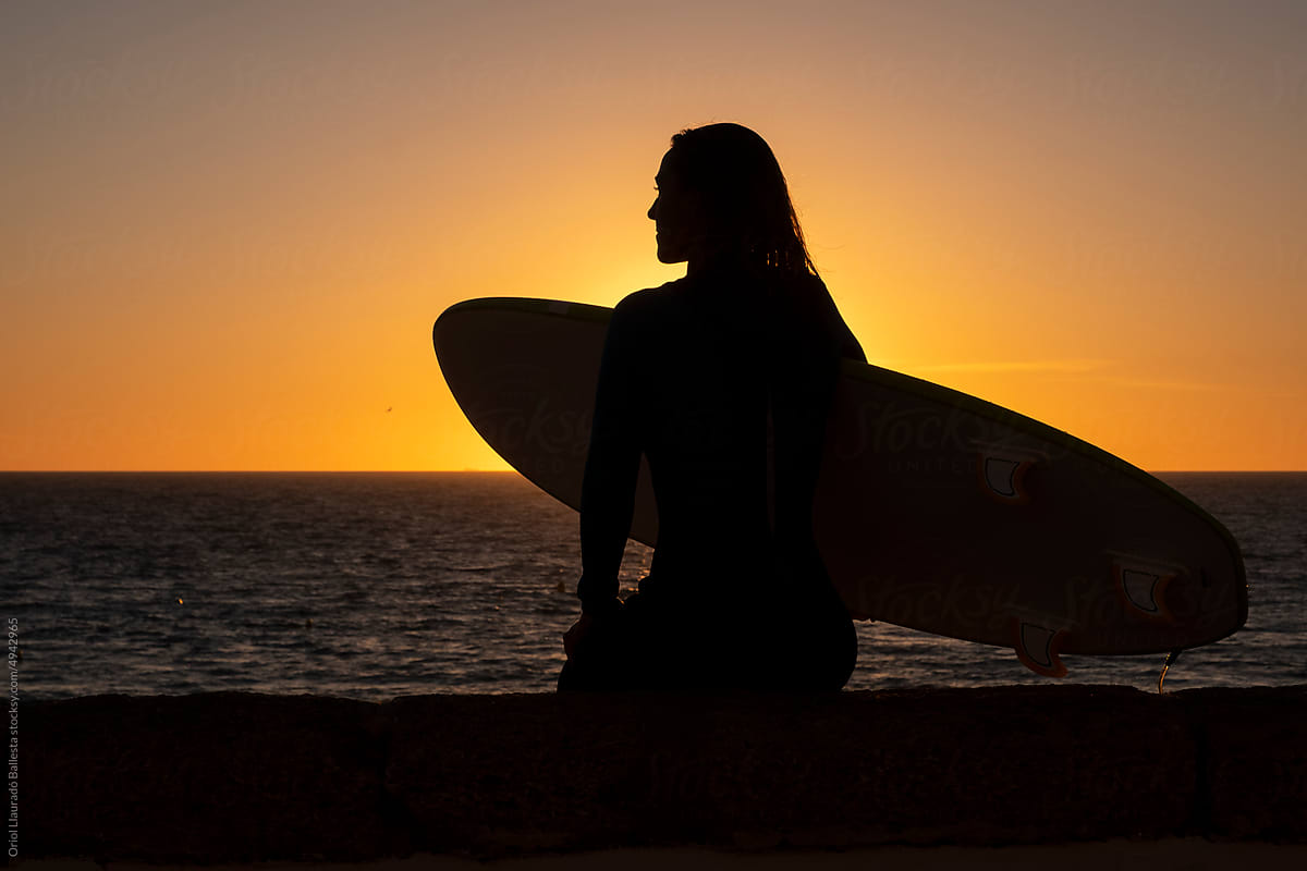 A surfer girl looking at a sunset