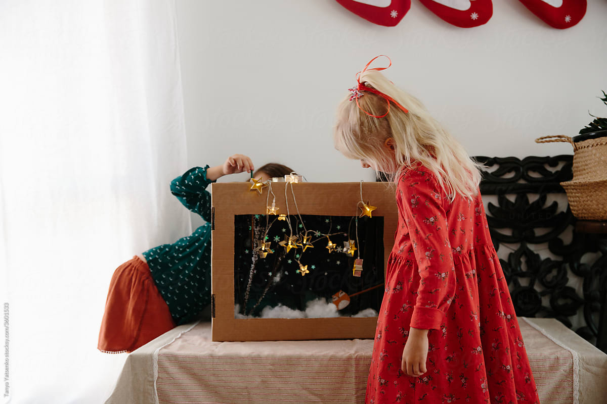 Girls playing with a hand-made puppet theatre at home