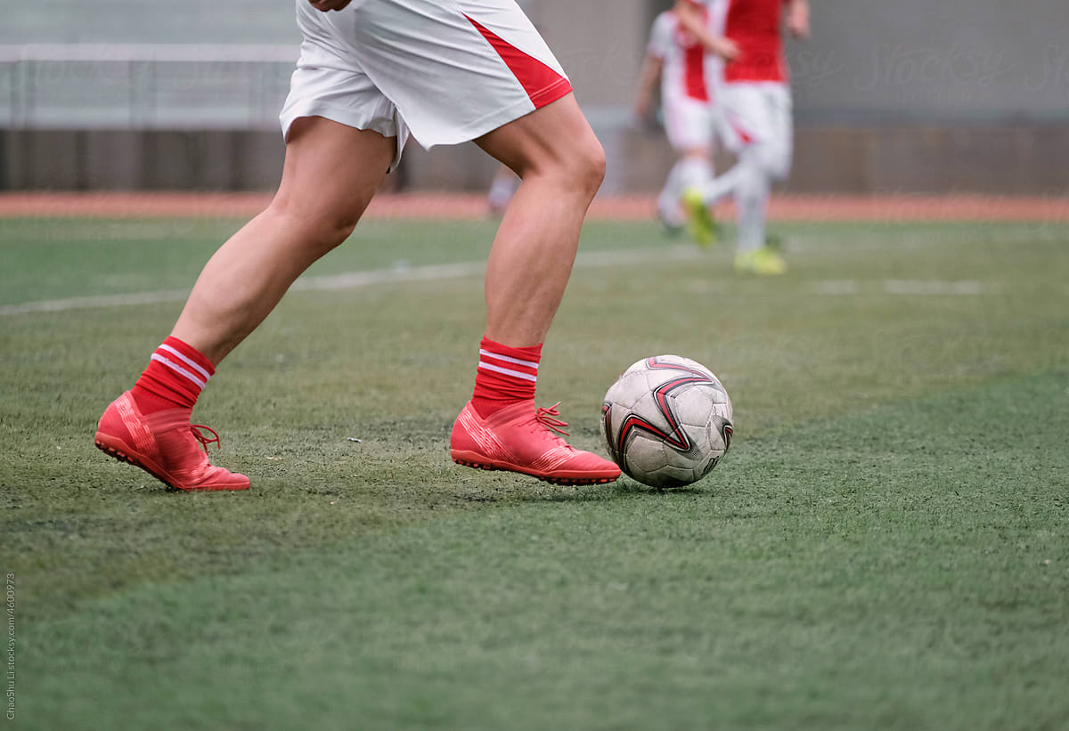 Closeup of football player\'s legs, breaking through with the ball