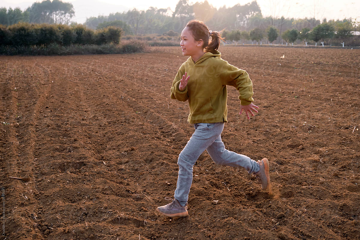 Asian little girl running in the empty outdoor ground