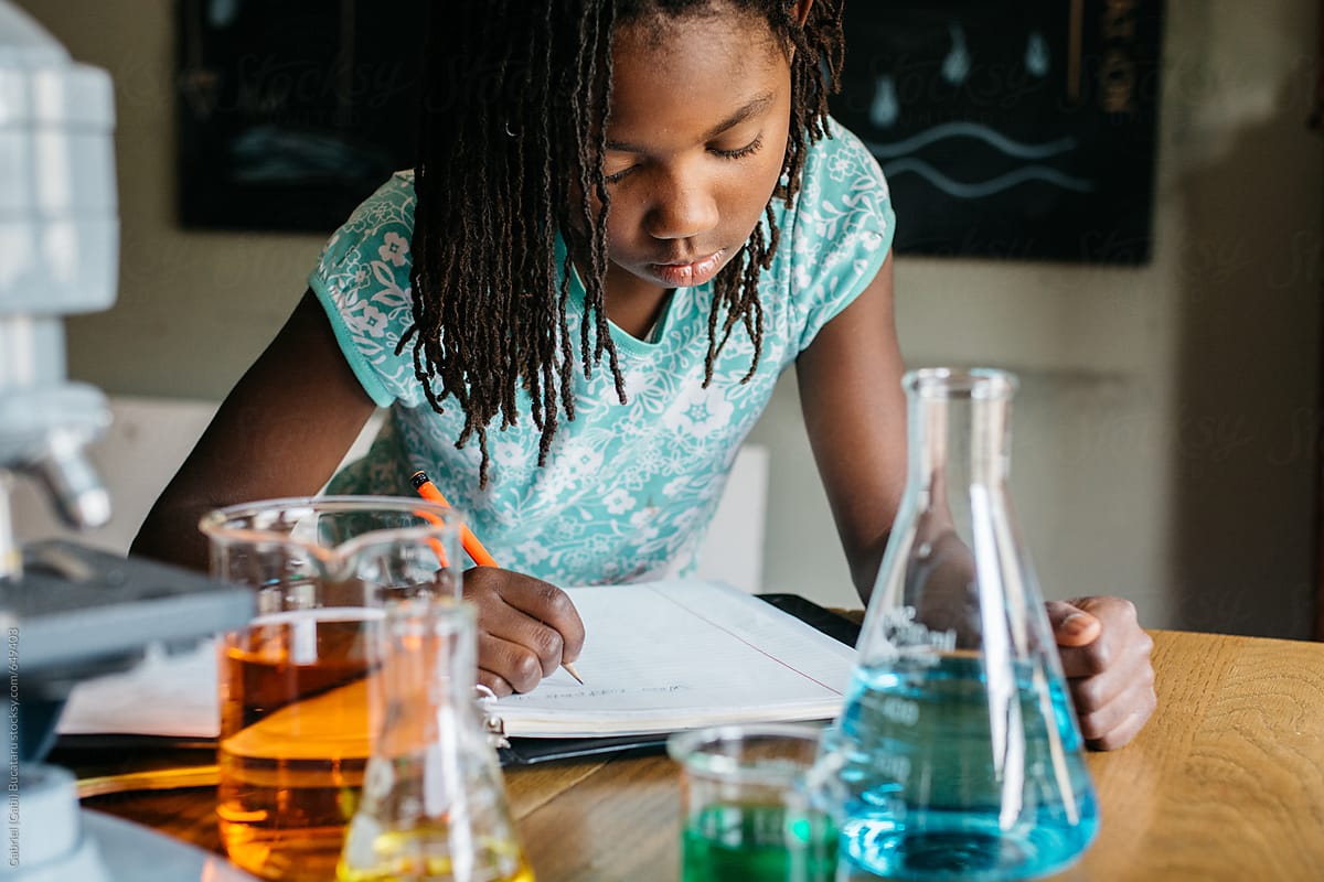 African American girl writing notes in a science class