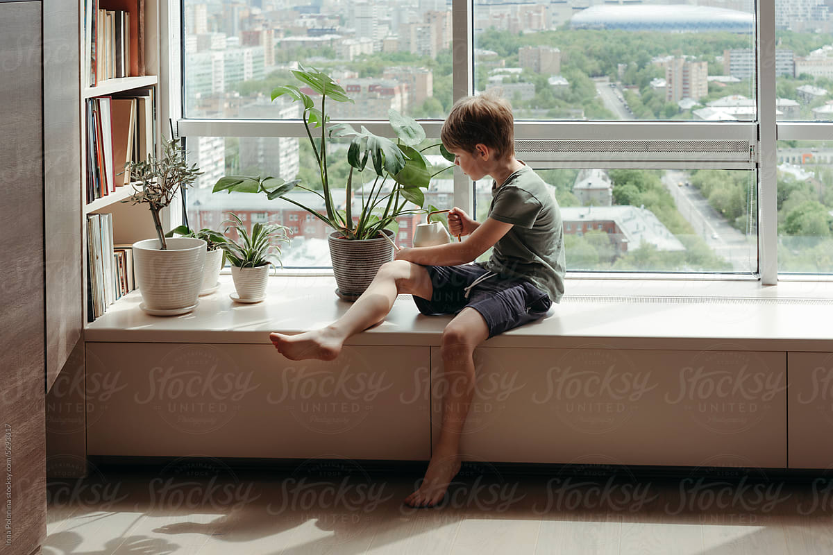 Kid takes care of green plants at home.
