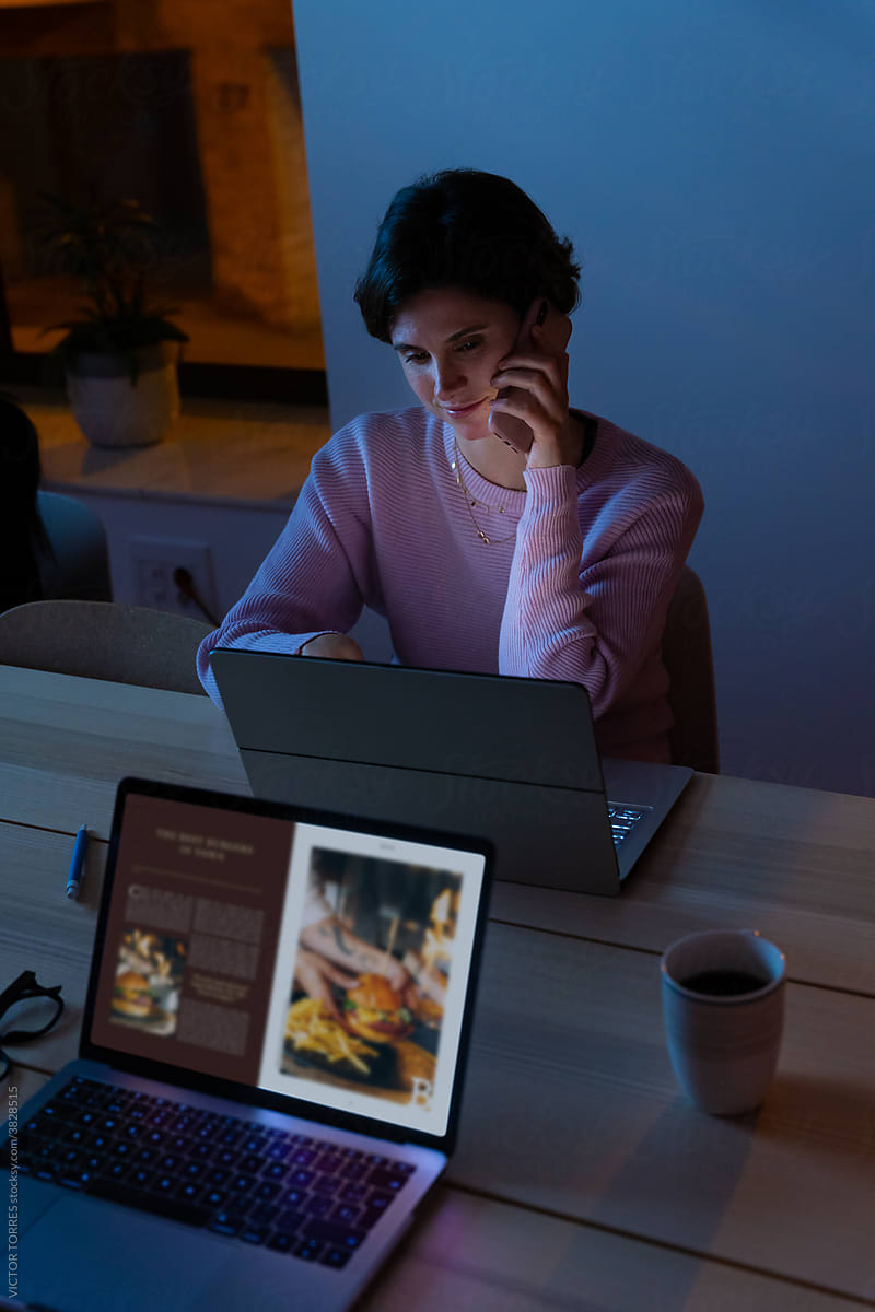 Smiling woman typing on laptop in dark office at night