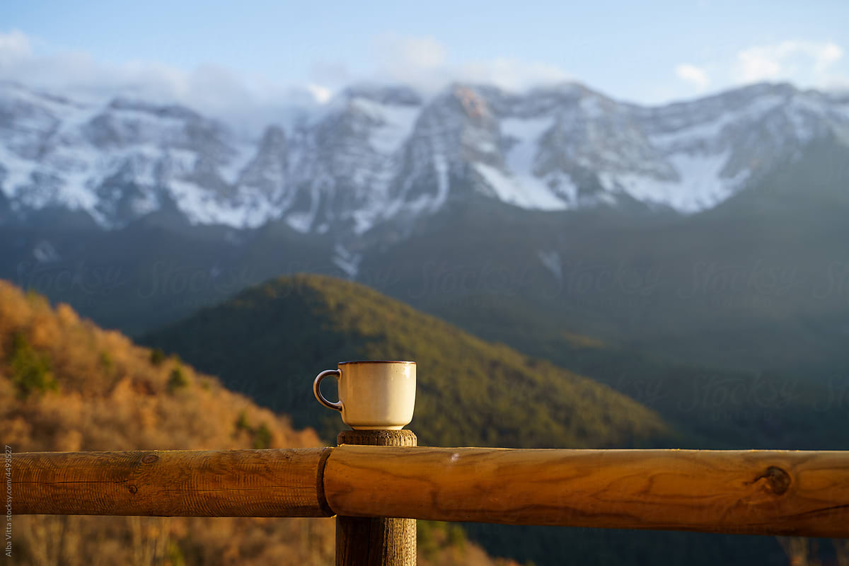 Coffee mug on banister in front of mountain scenery