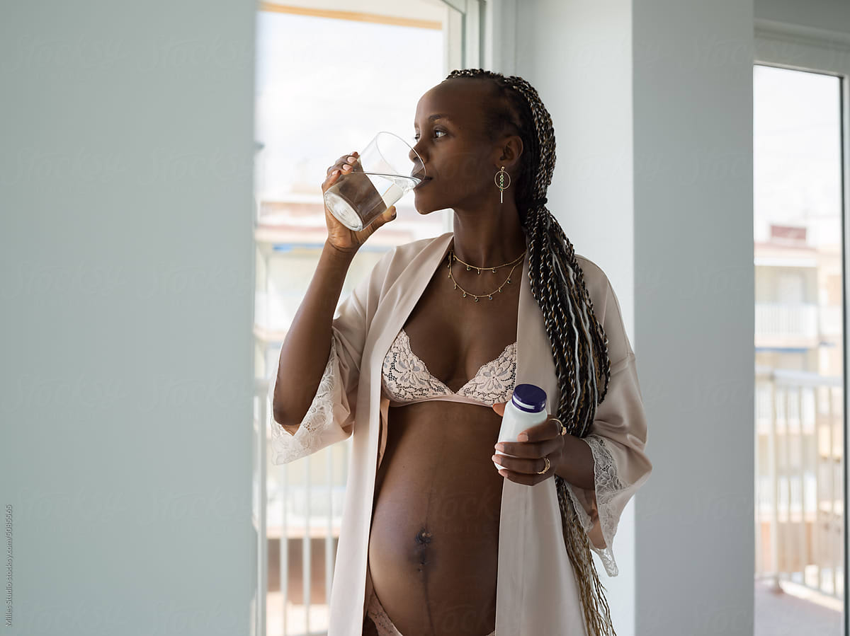 Pregnant woman drinking water while taking supplements