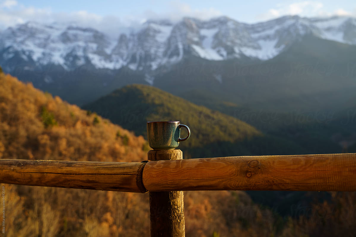 Coffee mug on banister in front of mountain scenery