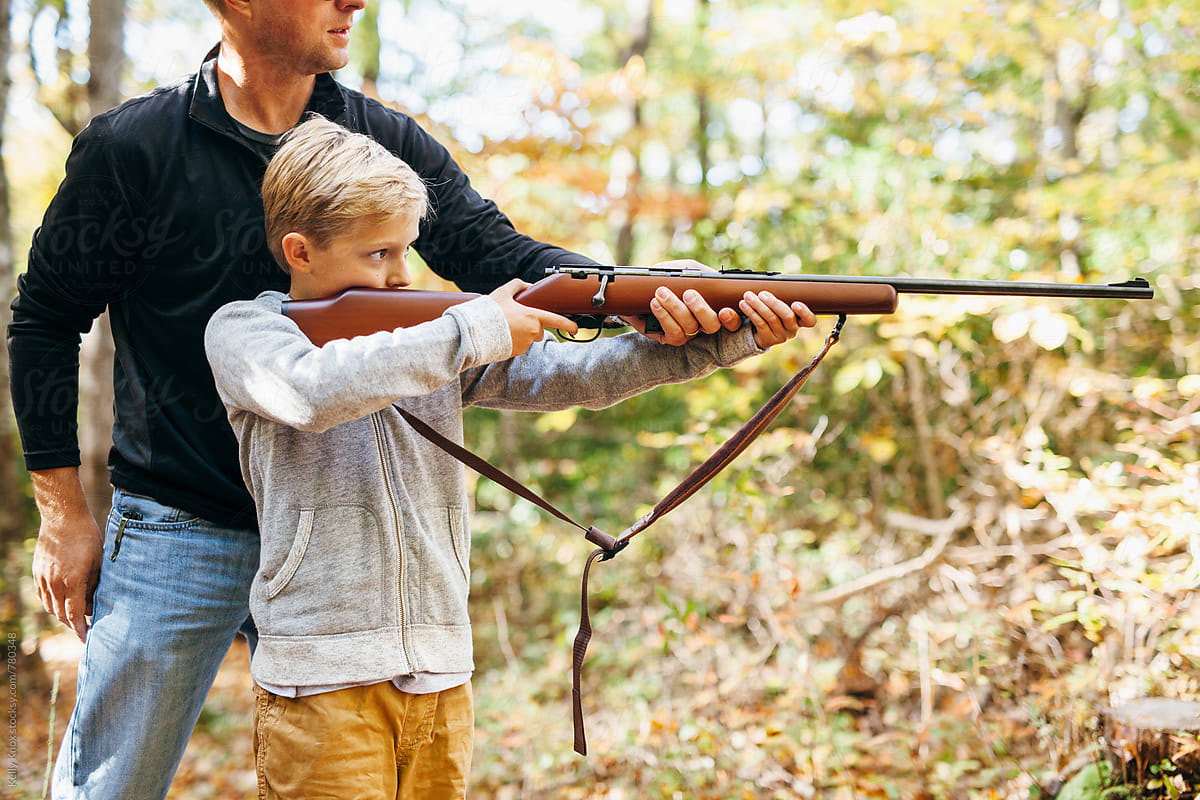 father teaching his son how to shoot a rifle by Kelly Knox
