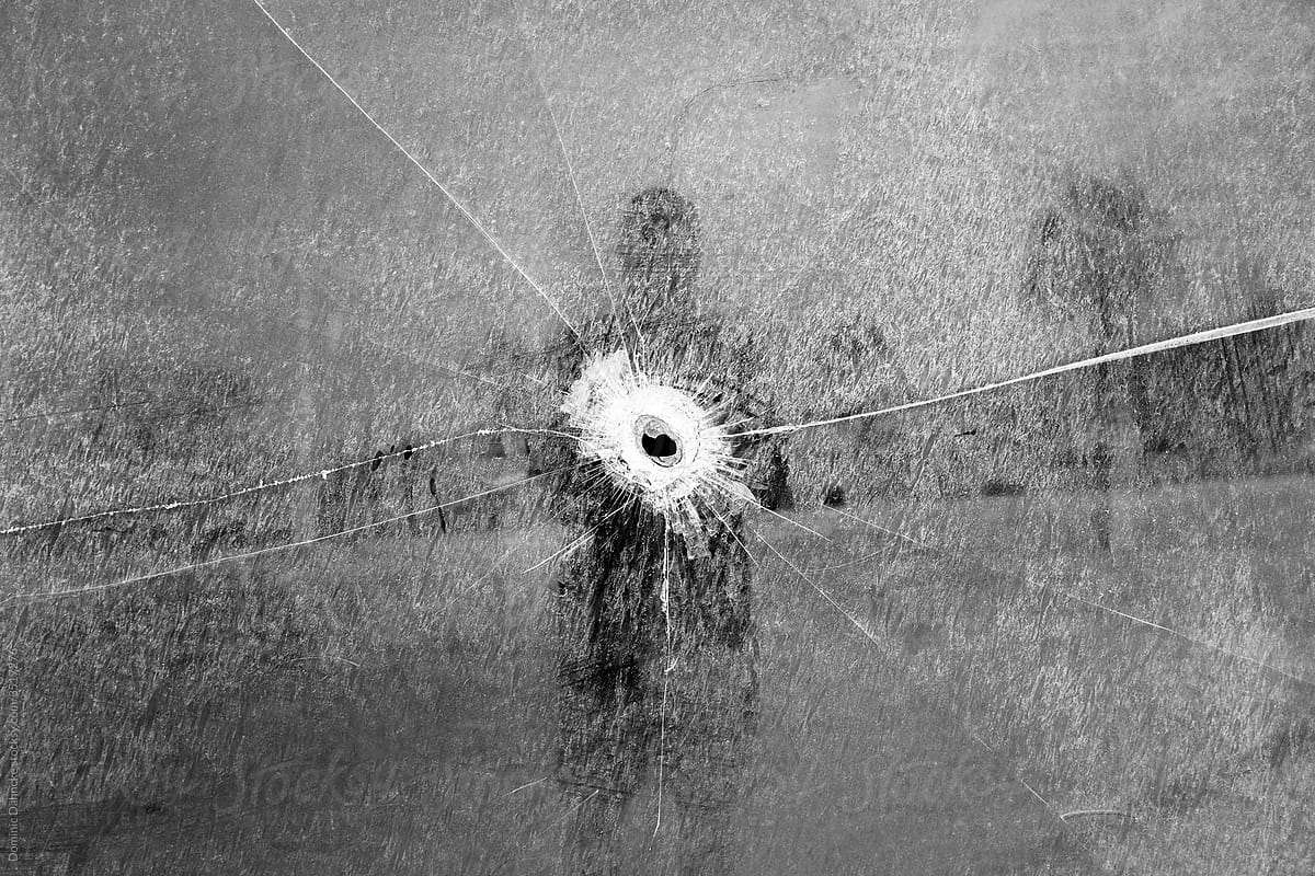 A self-portrait featuring a glass pane perforated by a bullet, symbolizing resilience and the transformation of pain into art