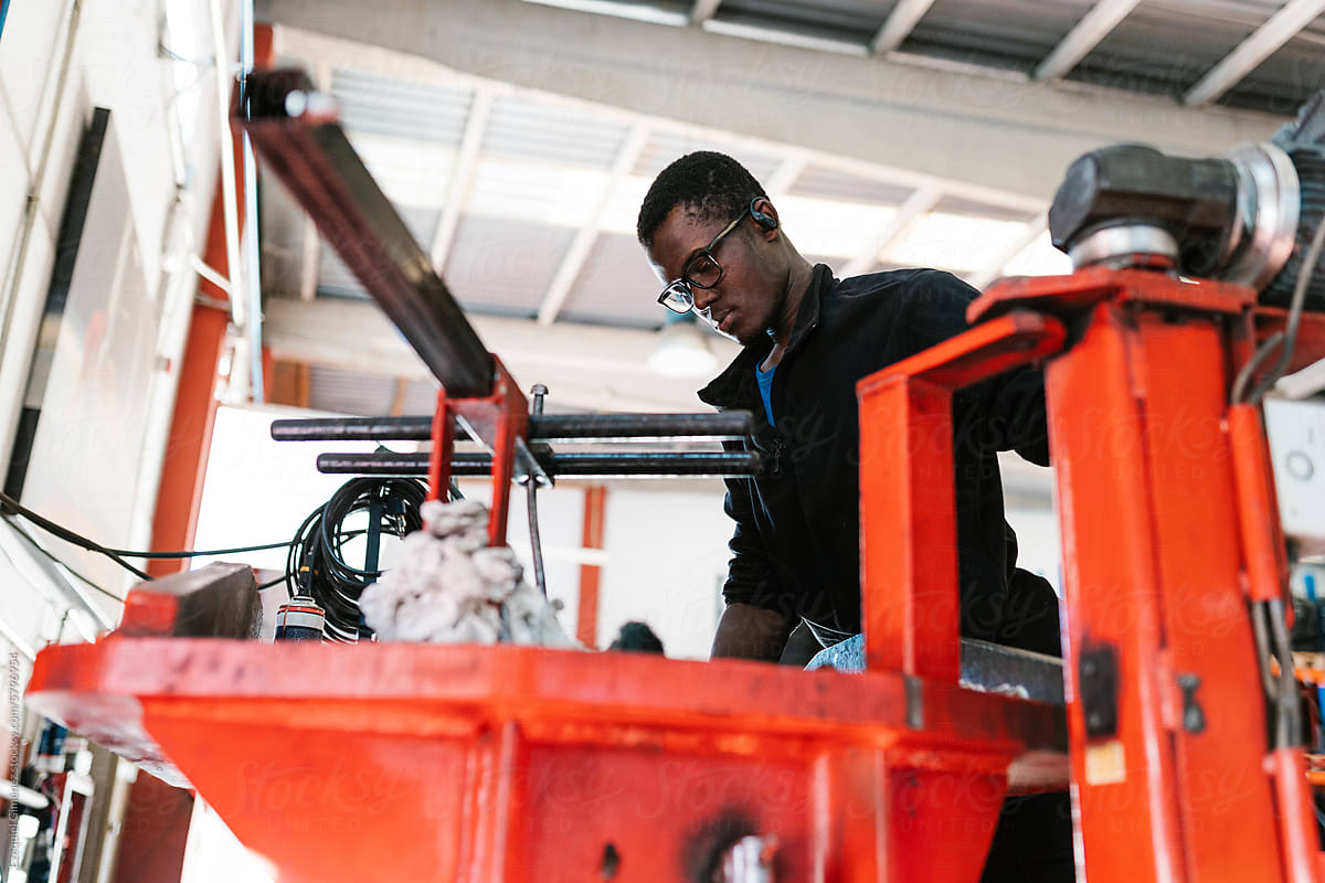 African American mechanic working on machine in garage