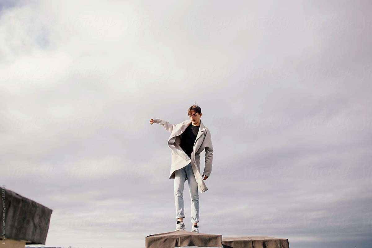 Portrait of young brunet man balancing on the roof