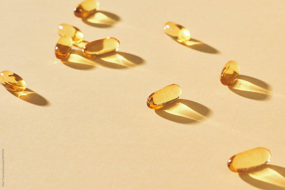 Fish oil in yellow capsules on a yellow background.