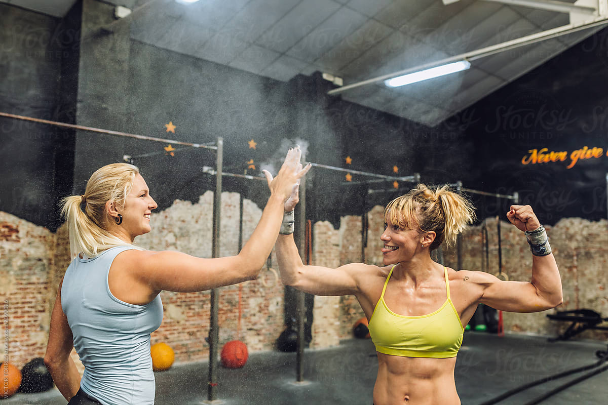 Muscular women high-fiving in gym