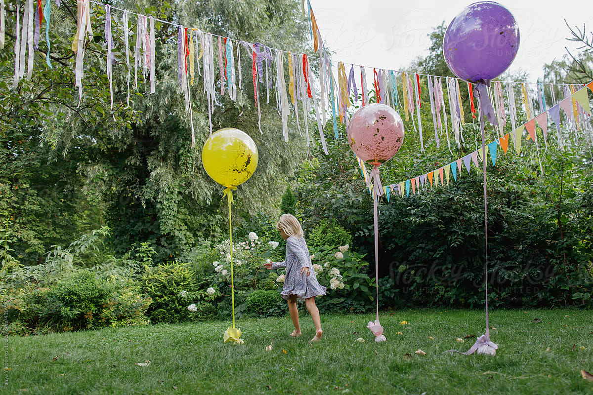 A birthday girl in the garden with three big balloons