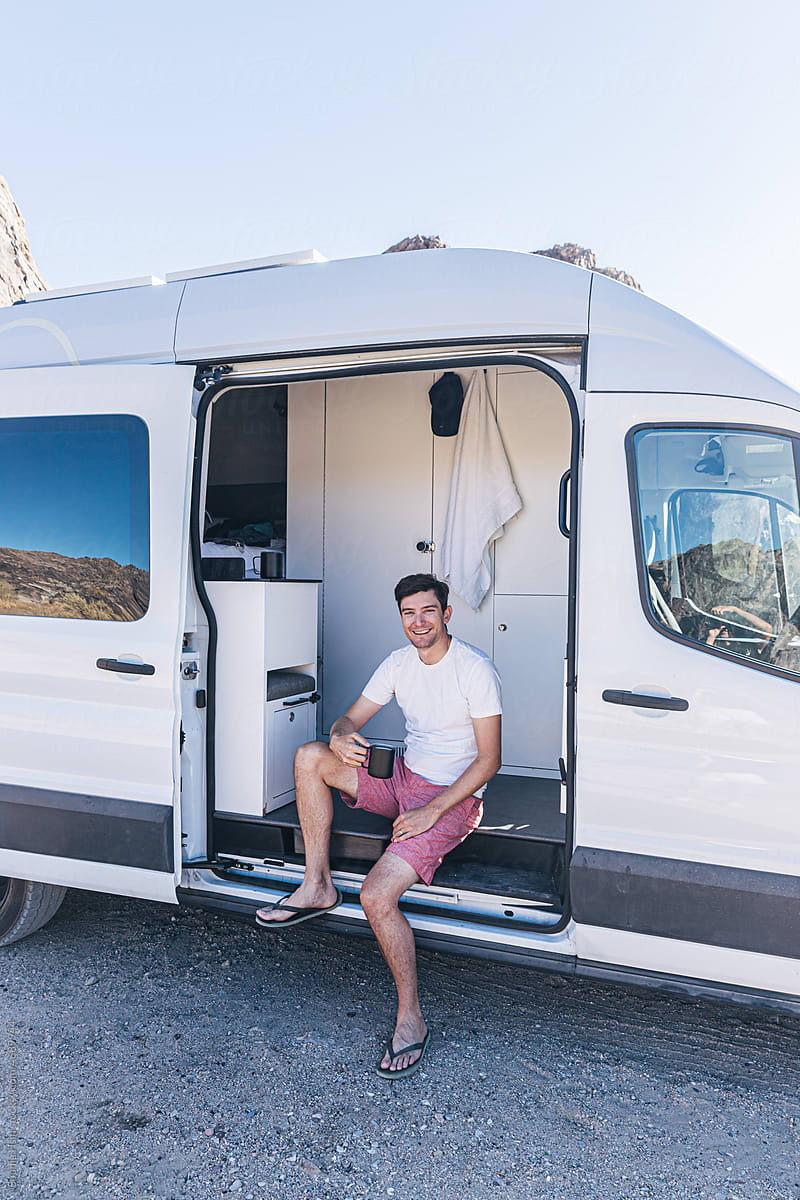 Man drinking coffee sitting in a camper van