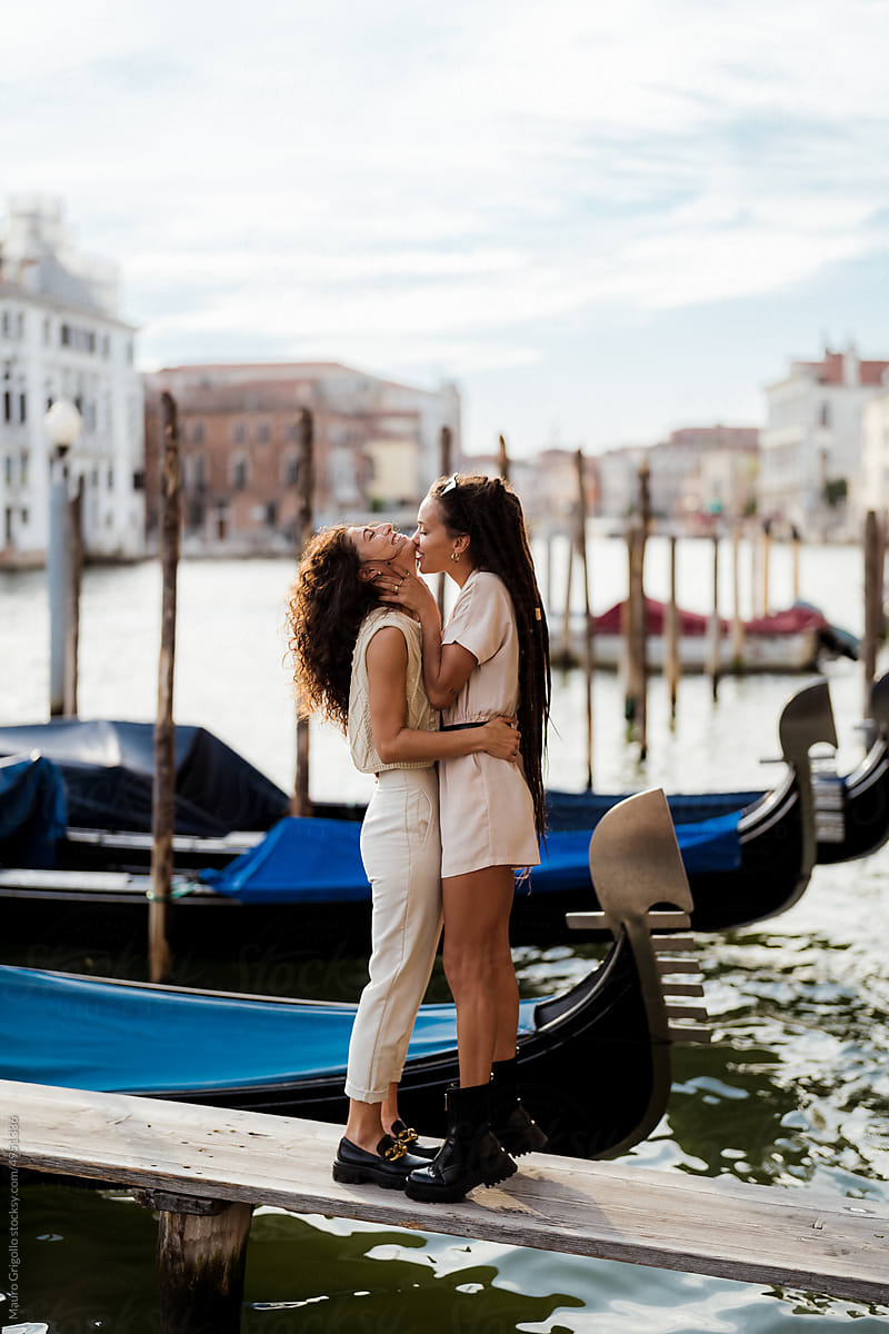Female lovers kissing along a river in Venice
