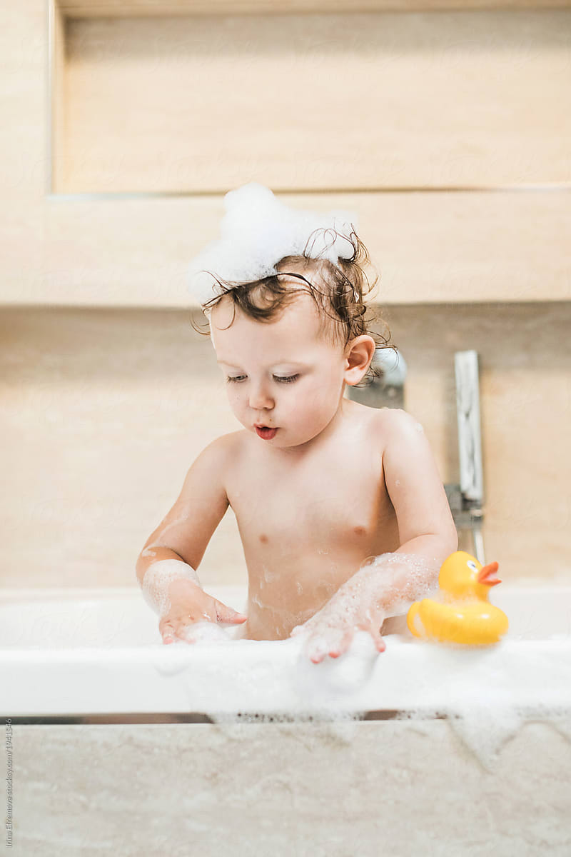 Toddler in a bathtub playing with soap foam