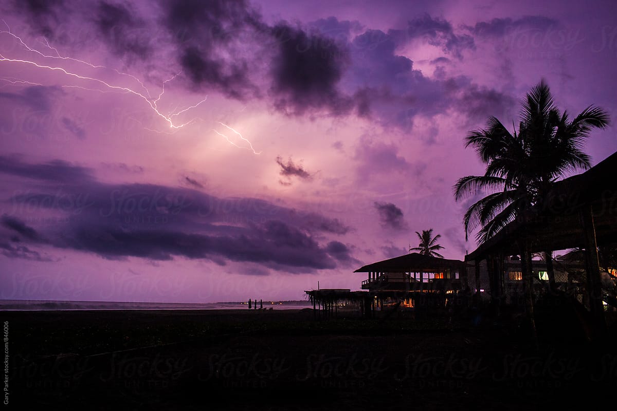 A purple sky lights up with lightning on a tropical Mexican beach