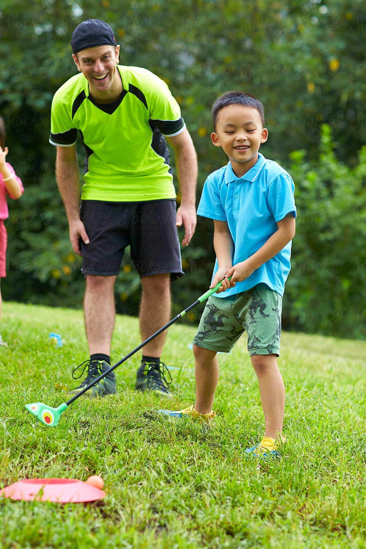 Caucasian English teacher teaching  Chinese kids  golf outdoor in the park