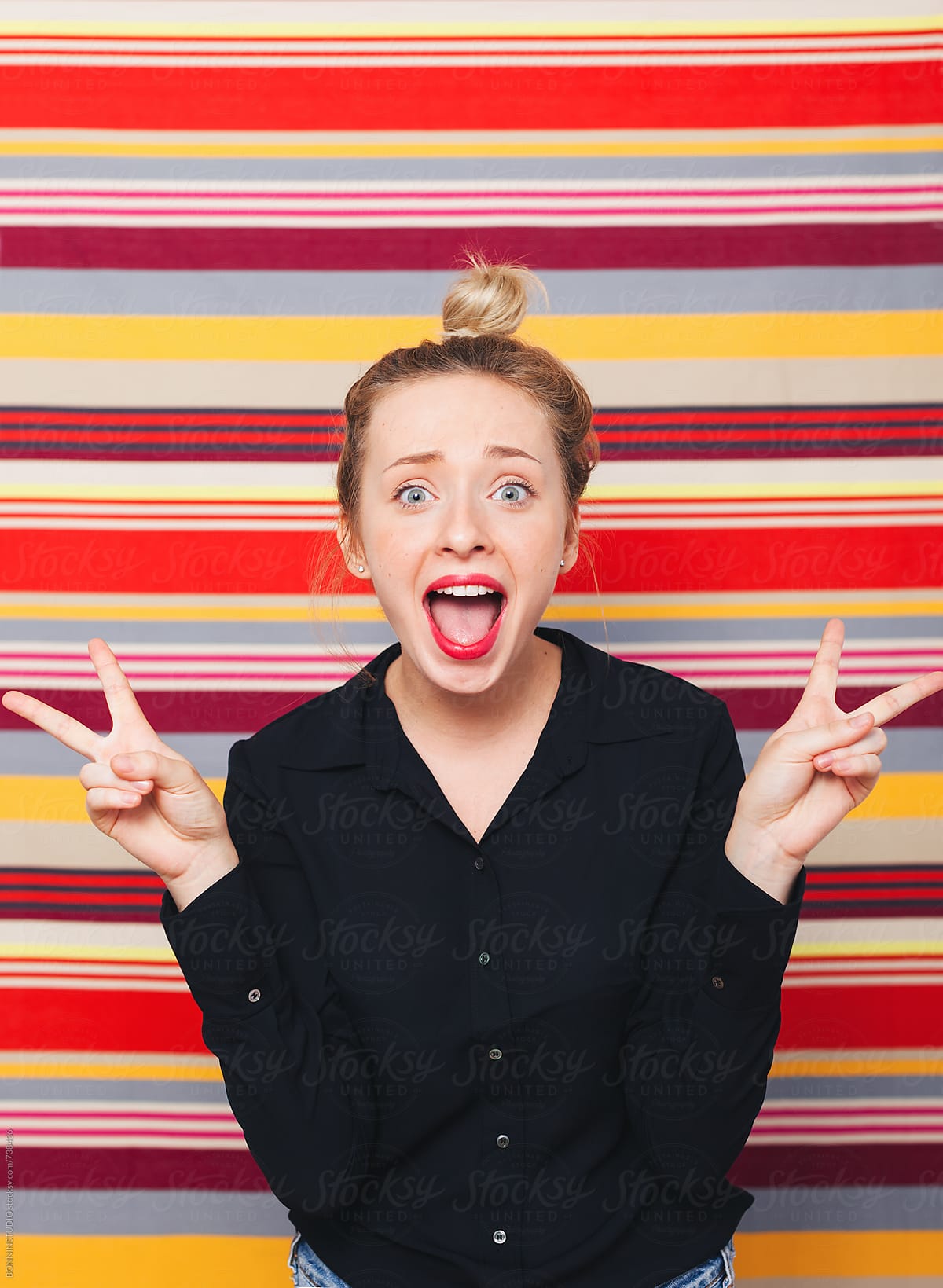 Portrait Of A Woman Making Funny Faces In Front Of A Striped Wall By Stocksy Contributor