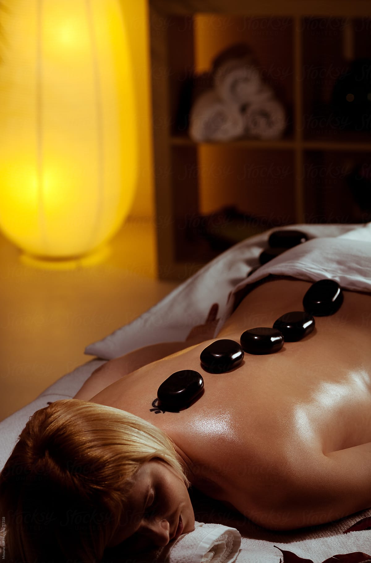 Woman enjoying spa treatment with hot stones.