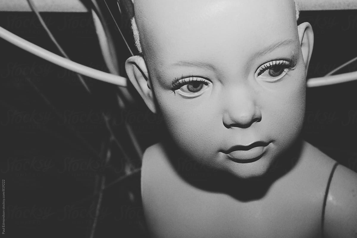 Close up of child mannequin, wires in background