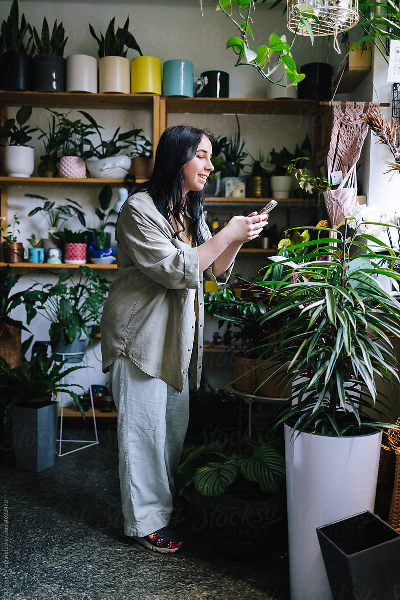 Female influencer photographing assortment of plants for blog