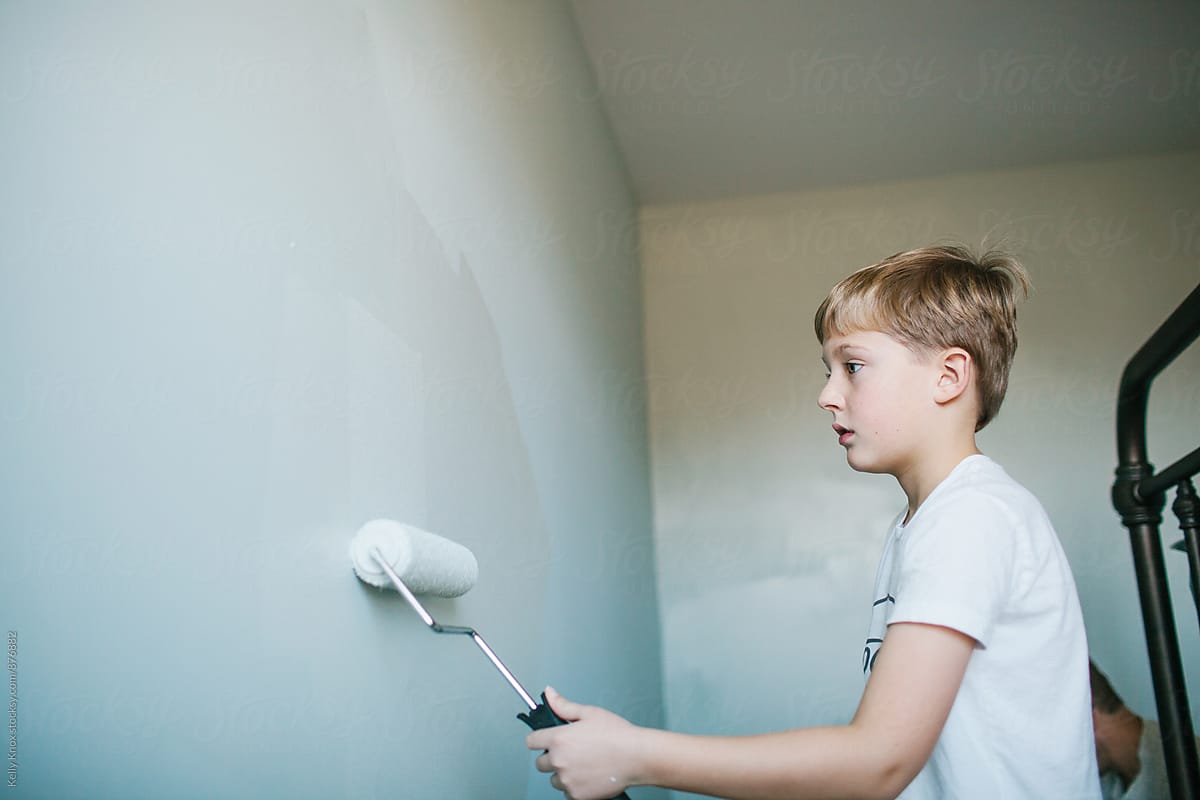 boy using a paint roller to paint his bedroom
