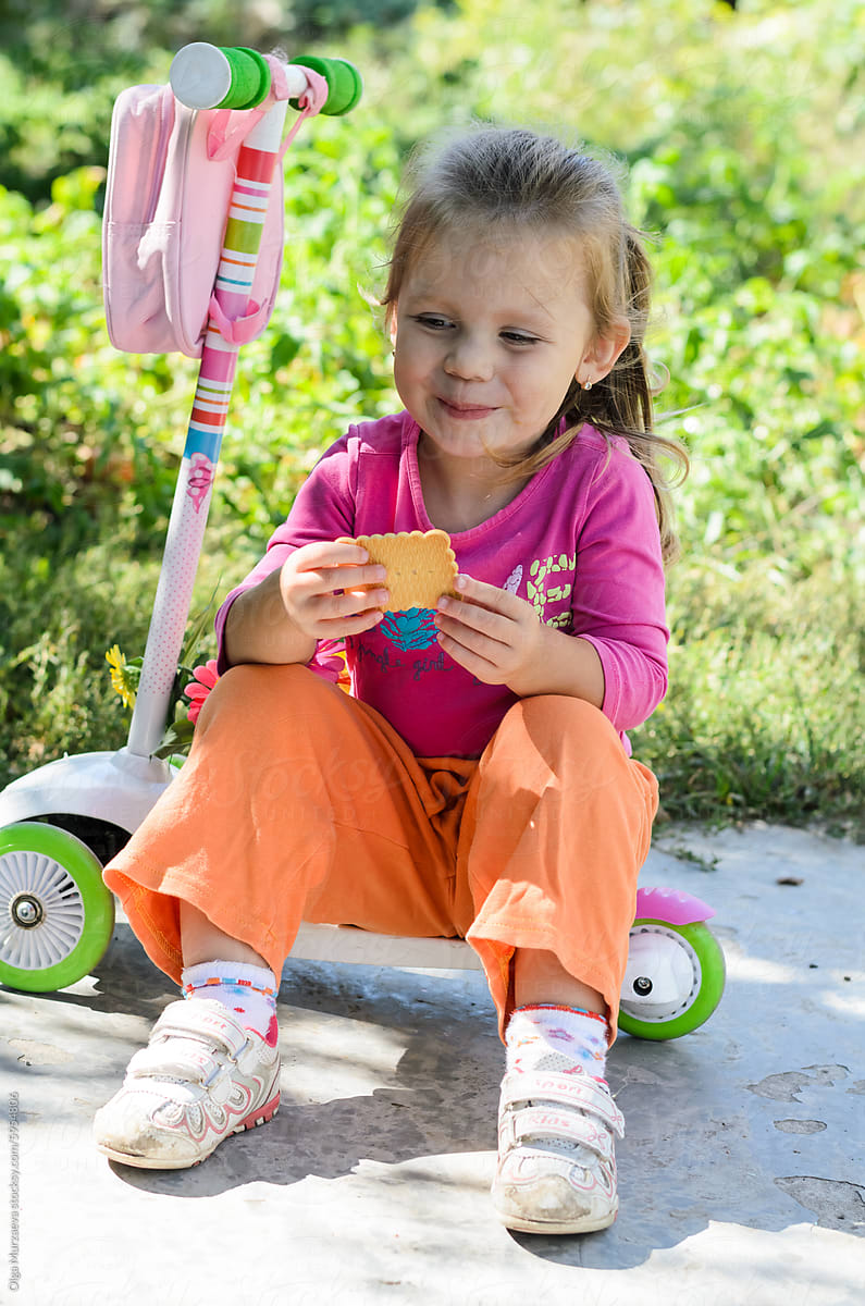 a little girl in a pink blouse and orange pants
